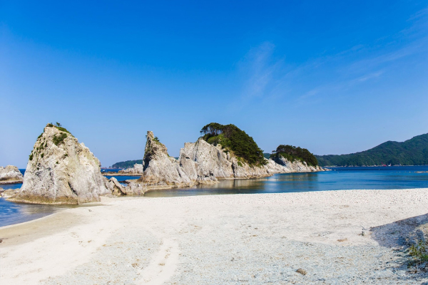 林立した白い岩とその内側の浜からなる美しい海浜の写真。
